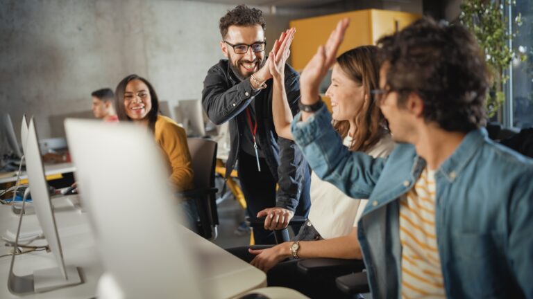 Team di lavoro festeggia un risultato davanti al computer